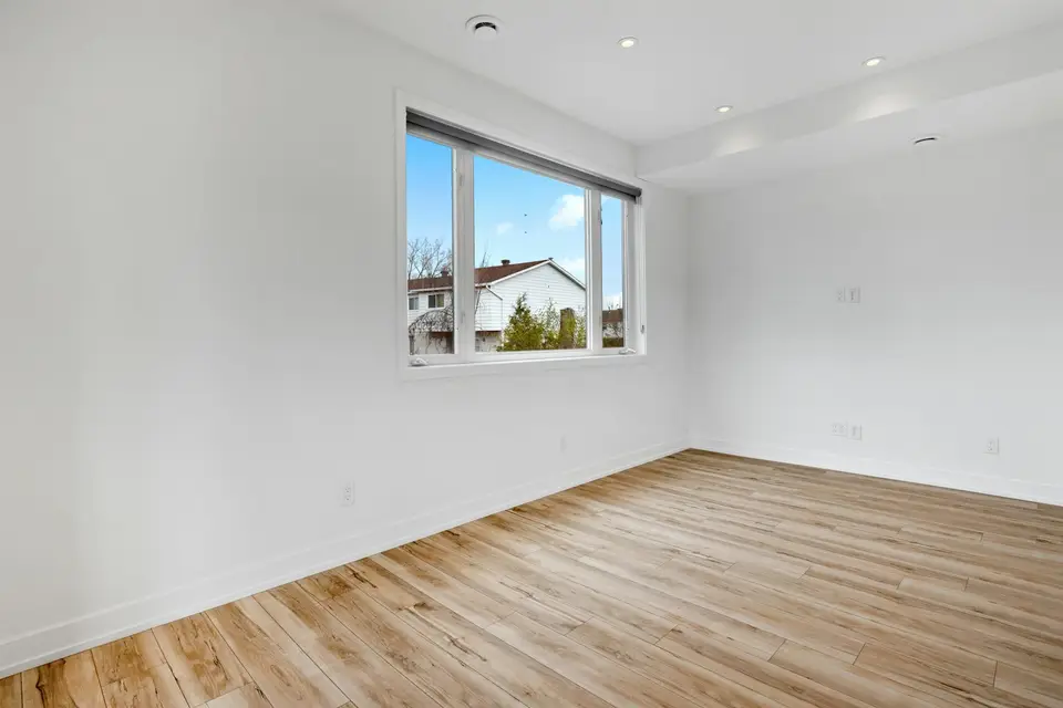 Installer fastening red oak hardwood strips over a plywood subfloor in a Massachusetts living room