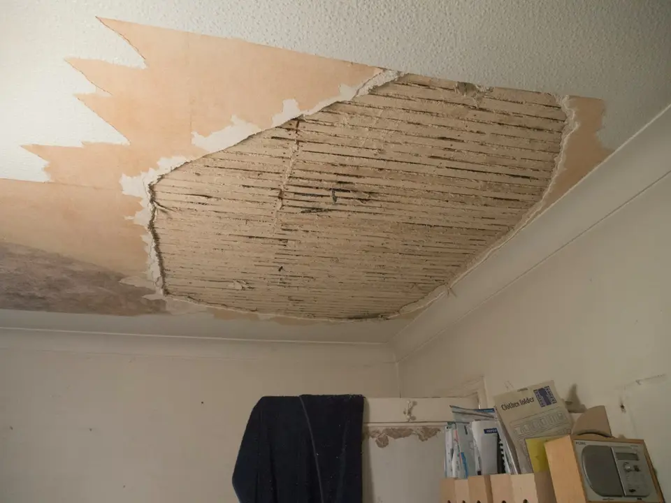 Air movers and a dehumidifier drying a living room with the lower drywall cut away above the baseboard